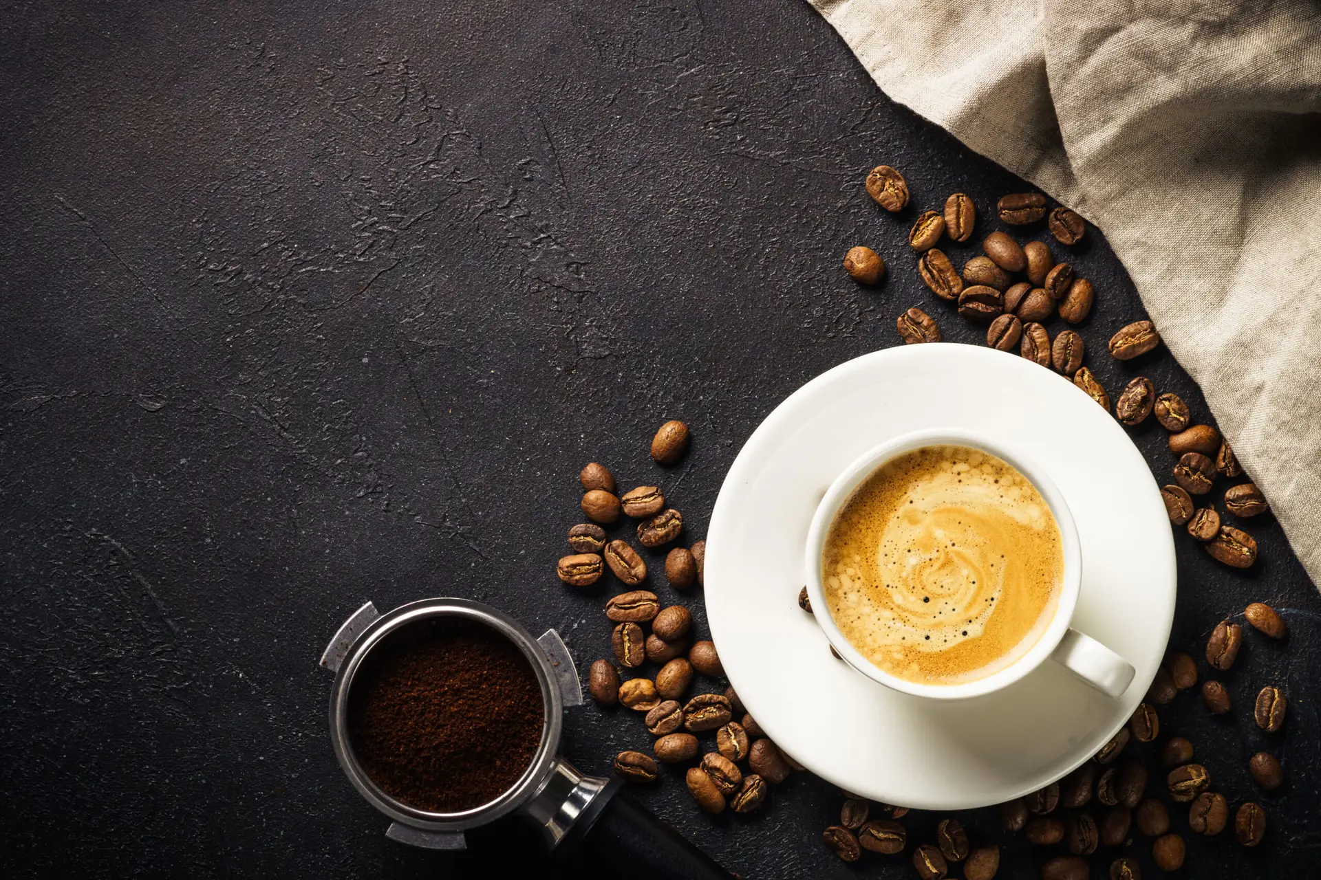 Coffee cup, coffee beans and filter holder at dark table . Top view image with copy space.